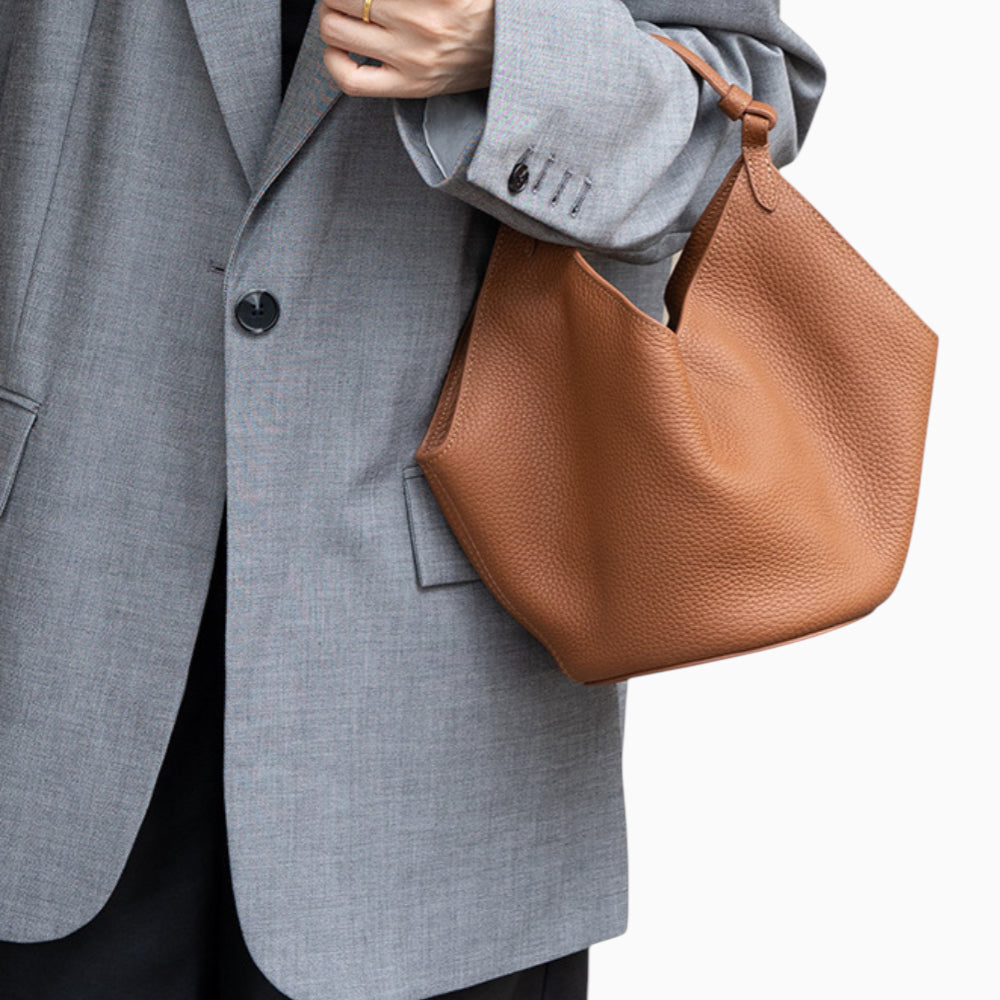 Sac à main en cuir caramel pour femme, modèle hobo souple Amaya, porté à la main par un mannequin.